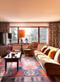 Fireplace, large windows, couch, coffee table, armchair, TV, rug, lamps, picture frames, decorative items