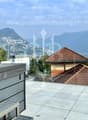 Terrace with tile floor, covered spa, houses in the background, glass railing, mountains in the distance