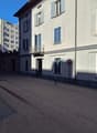 Building with multiple windows, balcony, grey walls, streetlight, trash bin, and a sign