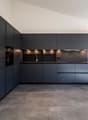 modern kitchen with black cabinets, tiled flooring, integrated oven and sink, under-cabinet lighting, large countertop