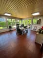 Spacious office with large windows, wooden ceiling, tiled flooring, office desk and chairs, and a cozy seating area.