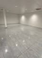 white walls, gray floor tiles, column in the middle, white ceiling, lights on the ceiling, empty room