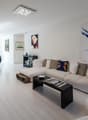 white walls, white floor, white sofa, black coffee table, art pieces on the wall