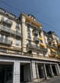 A multi-story building with many balconies, yellow awnings, and a classical architectural style