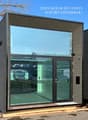 tiny house, glass windows, double doors, wooden siding, carport visible