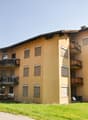 Three story yellow building, modern design, multiple balconies with tables and chairs