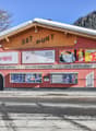 Red building with text 'SOT PLUNT', three signs for sport, perfume, and restaurant