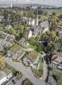 Multiple residential buildings, green roofs, garden areas, church, large open field, roads