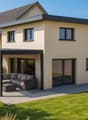 Two story house with beige walls, grey roof, covered outdoor seating area with a sofa, sliding glass doors