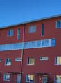 Red building with multiple windows, multiple floors, entrance with awning, number 32 on the right side