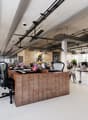 modern open space office with desks, monitors, ceiling fans, brick accent wall, white floors, various plants