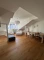 open space with wooden floor, white walls, large windows, dining table, chairs, sofa, ottoman, potted plant, chandelier