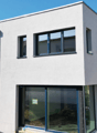 Modern 2-story house, white exterior, large windows, glass doors, trees in the background