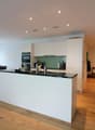 modern kitchen with white cabinets, black countertops, island, dining area, wooden floor