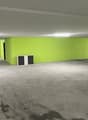 Empty parking area with green walls, concrete floor, column, two small doors, and two cabinets.