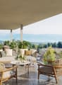 Balcony with outdoor furniture, glass railing, plants, table, view of mountains