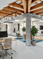 modern office space with wooden beams, glass walls, desks, chairs, plants, meeting table, monitors, and lamps