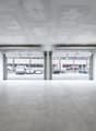 Empty garage with two open doors, concrete floor, white walls, metal staircase