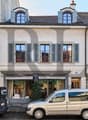4 story building, white walls, gray shutters, storefronts on first floor