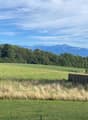 open field with high grass, wooden fence, mountain range in the distance