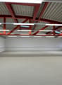 Empty room, steel roof, white walls, fluorescent lighting, concrete floor, windows, doors