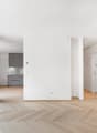 une photo d'une maison moderne avec des murs blancs, des sols en bois et une grande entrée ouverte sur la cuisine / a picture of a modern home with white walls, wooden floors, and a large open entran