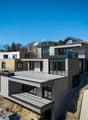 Modern house, multiple levels, balconies, gray brick, glass windows, under construction