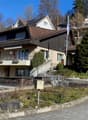 3-story house, brown roof, beige facade, several balconies, staircases