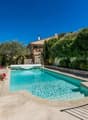 Swimming pool, stone wall, metal railing, plants, flowers, house in the background