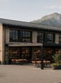 modern building, large windows, outdoor seating area, surrounded by mountains