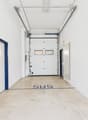 Empty storage room with concrete floor, white walls, blue trims on doors, two doors on left, two doors on right