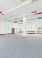 Empty room, white walls, gray carpet, multiple large windows, white column in the center, square ceiling tiles