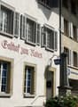 white facade, multiple windows with shutters, sign reading Balthof zum Raben