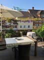 Balcony area with a table, chairs, umbrella, potted plants, and a view of the city