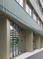 modern office building, glass facade, multiple floors, balcony with metal railings, wide entrance