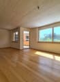 large empty room, hardwood floors, glass doors leading to balcony, large windows