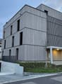 modern building, gray exterior, multiple windows, entrance with canopy, underground parking