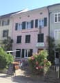 pink building, green shutters, outdoor seating, sign reading Gasthaus zur Linde, flowers, gate