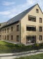 2 story building, beige color, raised ground floor, multiple balconies, solar panels