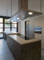 modern kitchen with island, two sinks, induction cooktop, oven, extractor hood, white cabinets, tiled floor