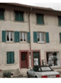 Apartment building, three stories, beige walls, green shutters, several parked cars in front