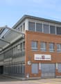 The image shows a multi-story commercial building with a brick facade and large windows. The building has a prominent sign that says 'Vina sa weine', indicating it is likely a wine-related business or facility. The building also has a covered walkway or e