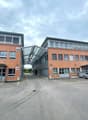 Multi-story commercial building with brick and glass facade, parking spaces in front, numbered entrances