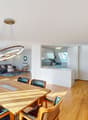 dining table with 6 chairs, round light hanging from ceiling, open kitchen, balcony, large windows