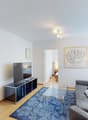 living room with TV, couch, coffee table, rug, artwork, open door to bedroom, sliding glass doors