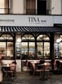 brasserie with arched windows, outdoor seating, black and white awning
