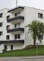 modern white building, 3 floors, balconies, green grass, street lights