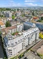 Aerial view of multiple residential buildings, some with rooftop terraces, gray roofs, street with cars, city view
