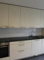 modern kitchen with white cabinets, black countertops, stainless steel oven, sink with faucet, electrical outlets