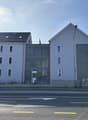 3 story building, white exterior, multiple windows, metal fence, street view